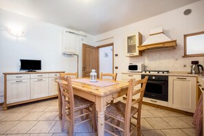 A compact kitchen with a dining table, chairs, a TV, a stove, and a microwave.