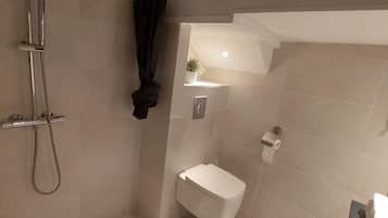 Een douche, handdoeken, zeep, toiletpapier