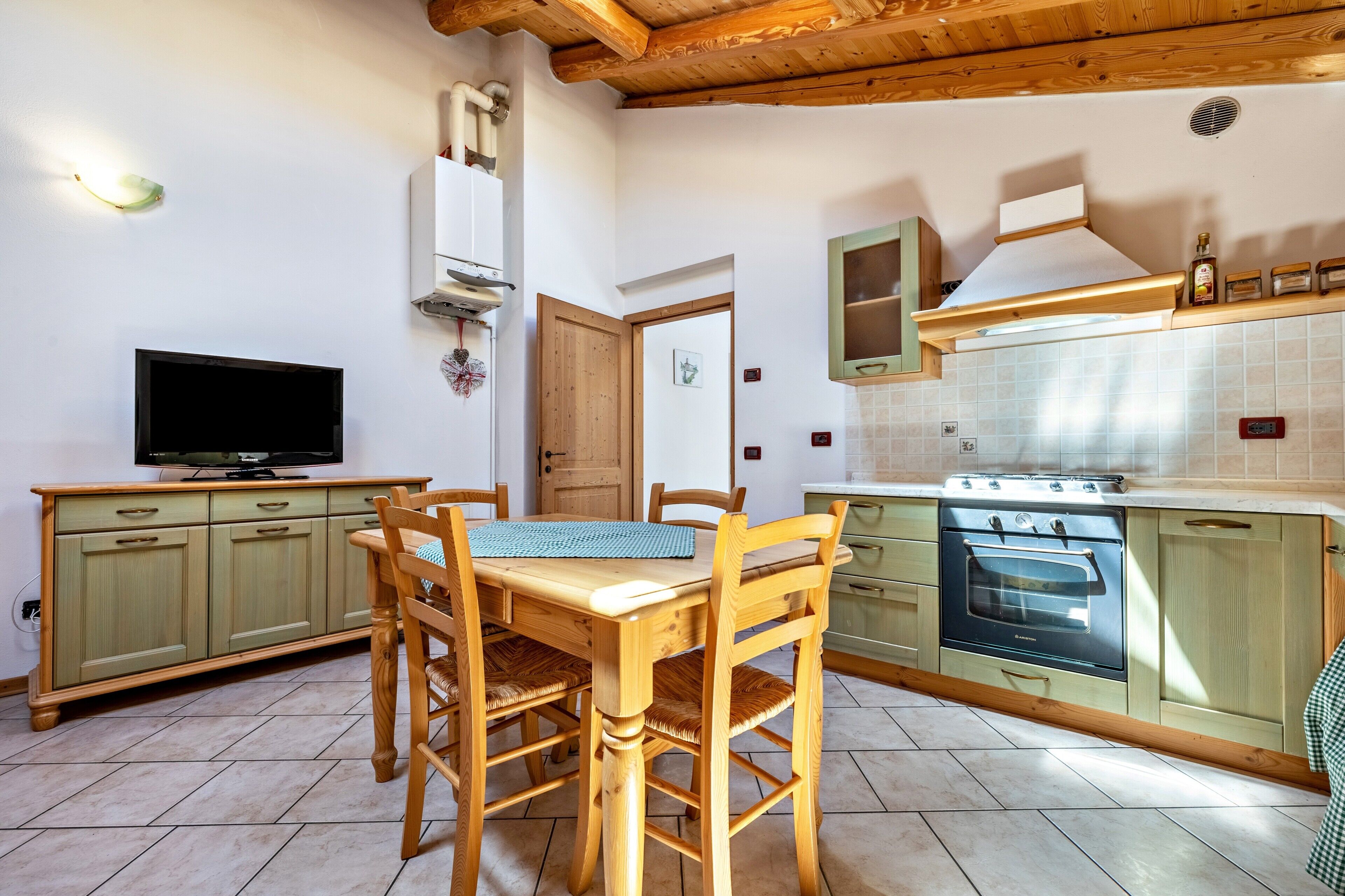 A kitchen with wooden cabinets, a stove, a microwave, and a television.