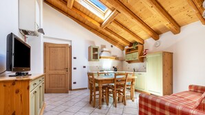 A kitchen with wooden cabinets, a dining table, and a red plaid sofa.