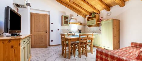 A kitchen with wooden cabinets, a dining table, and a red plaid sofa.