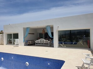 Ein modernes Gebäude mit Pool, einer weißen Bank und einem Tisch.