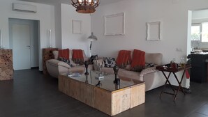 Un salon moderne avec une table basse au centre, un canapé agrémenté de coussins rouges et un lustre.