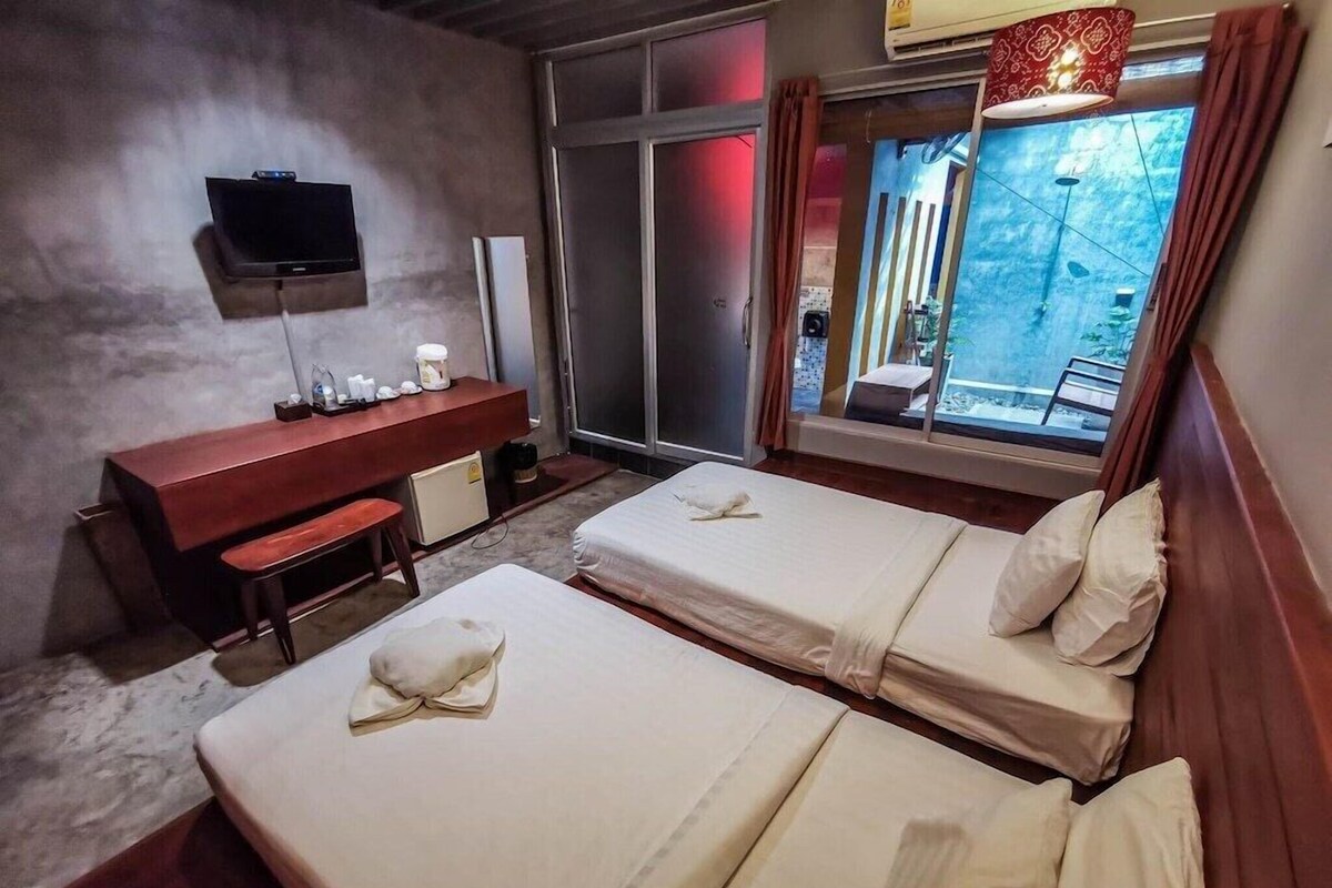 Een hotelkamer met twee bedden, een bureau, een televisie en een raam met gordijnen.