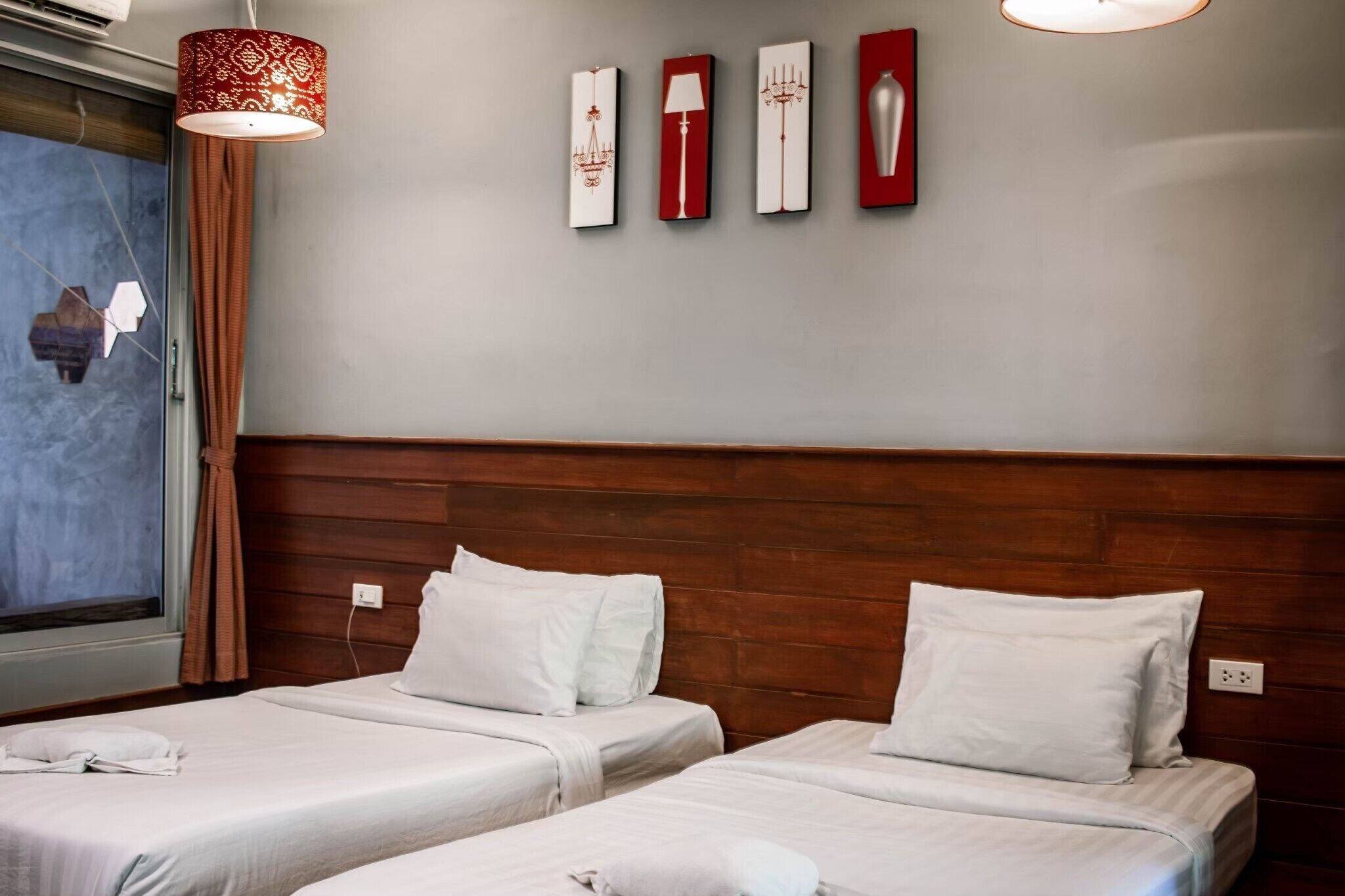 A hotel room with two beds, a wooden headboard, a window with a view, and wall-mounted artwork.