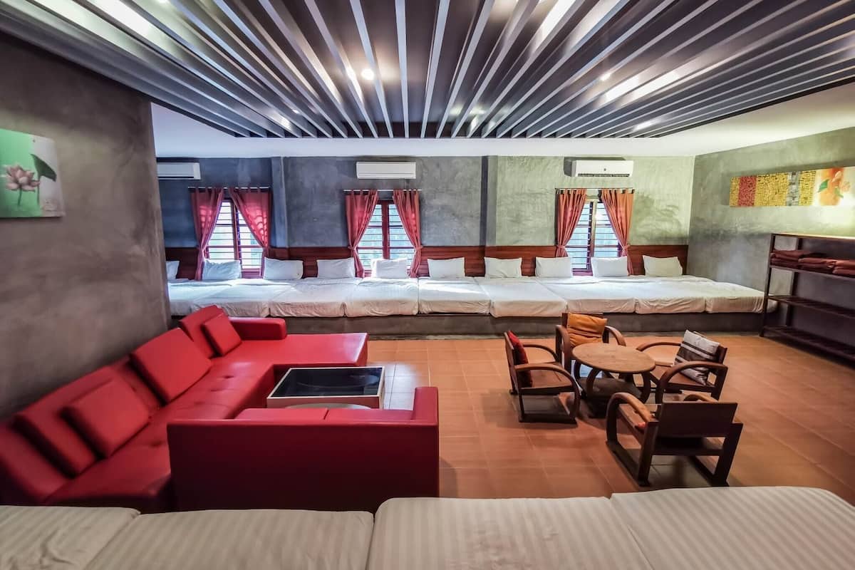 A hotel room with a large bed, a red sofa, and a small table.
