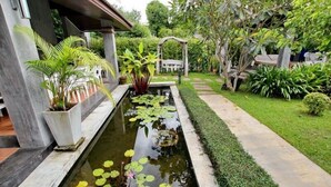 Een rustige tuin met een rechthoekig vijver, weelderige begroeiing en een verzorgd pad.