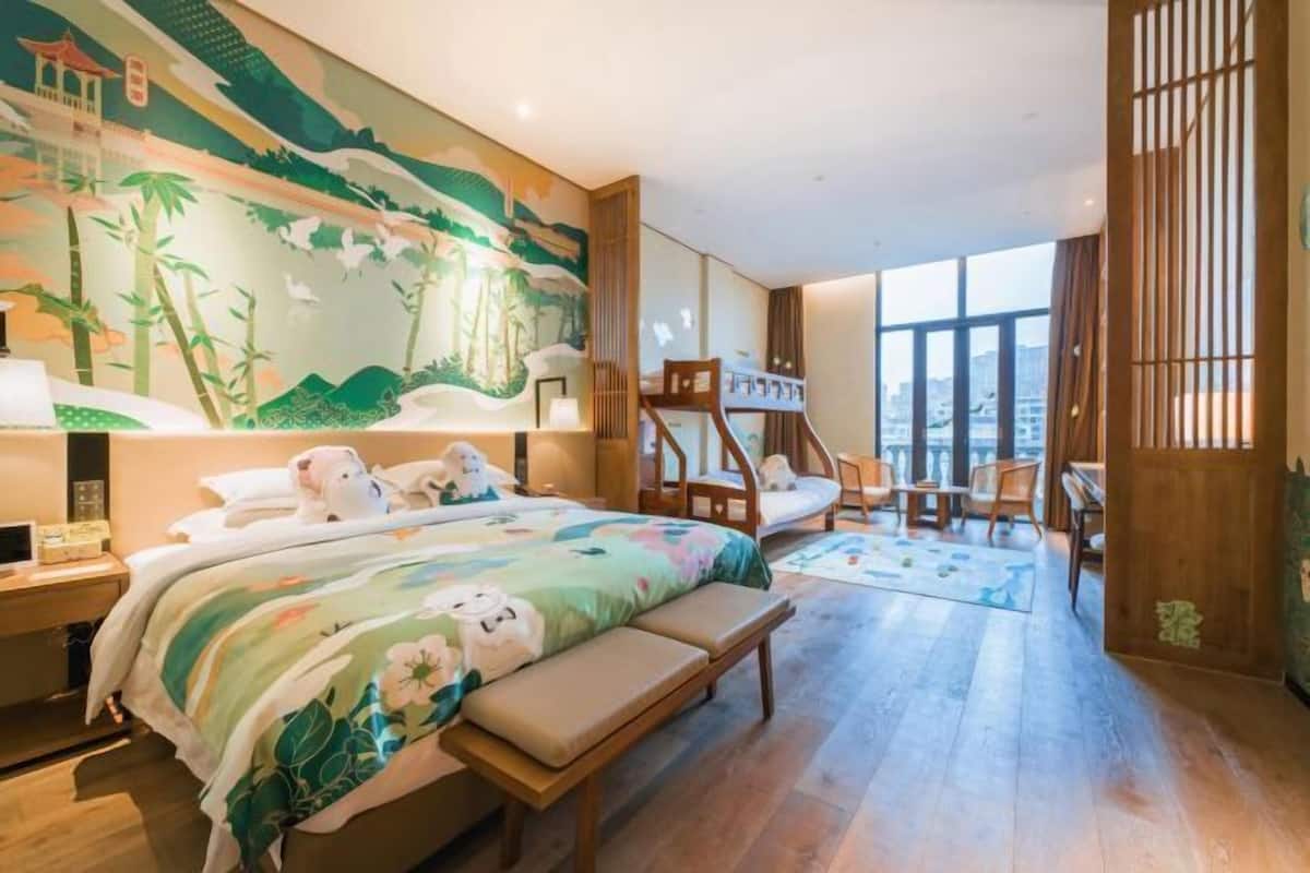 A hotel room with a large bed, a desk, a chair, and a view of the city.