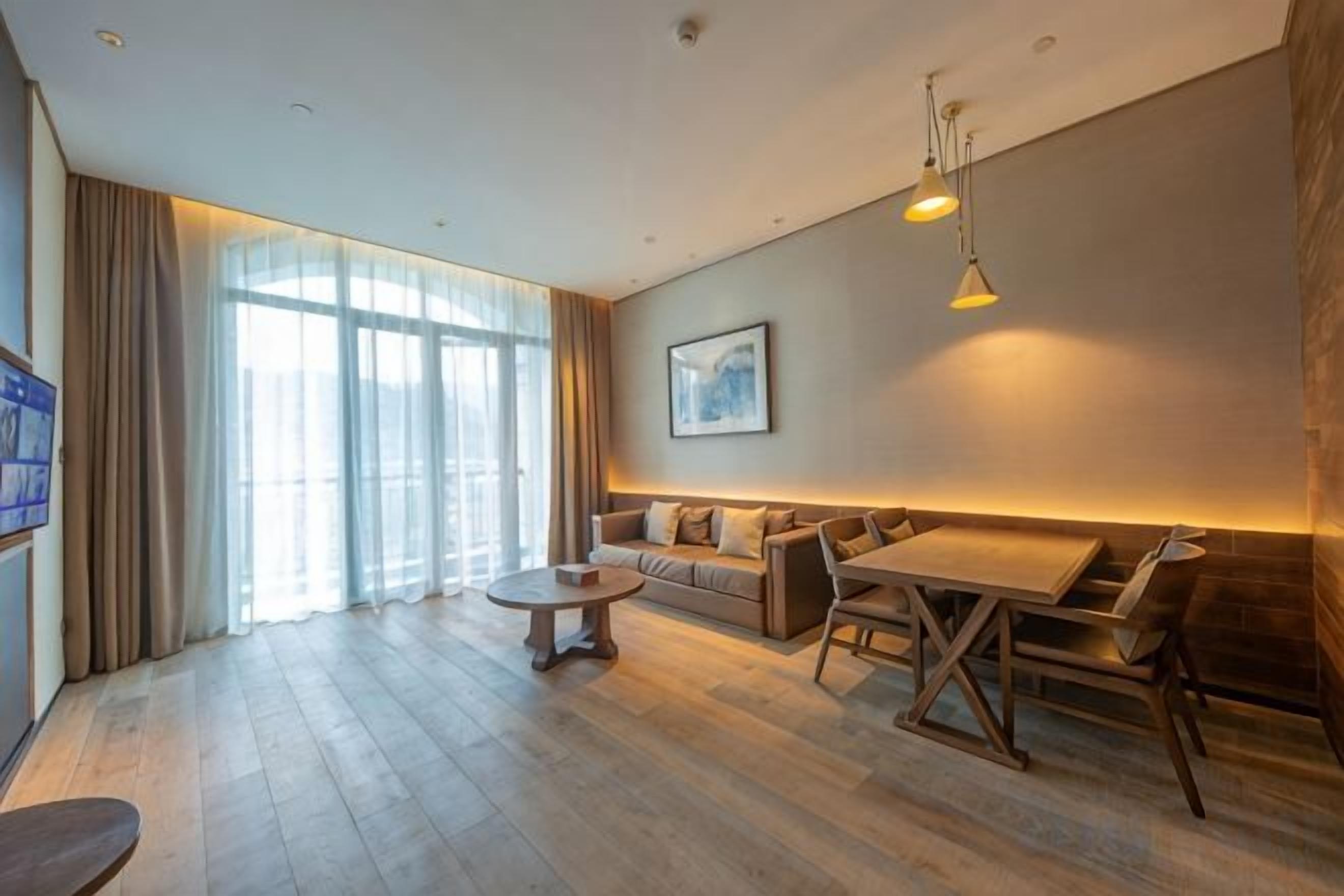 Una sala de estar moderna con un conjunto de sofás, una mesa de comedor y un televisor a la izquierda.