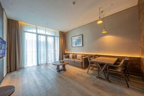A modern living room with a sofa set, a dining table, and a TV on the left. - Azure Reserve Deqing (DEQING)