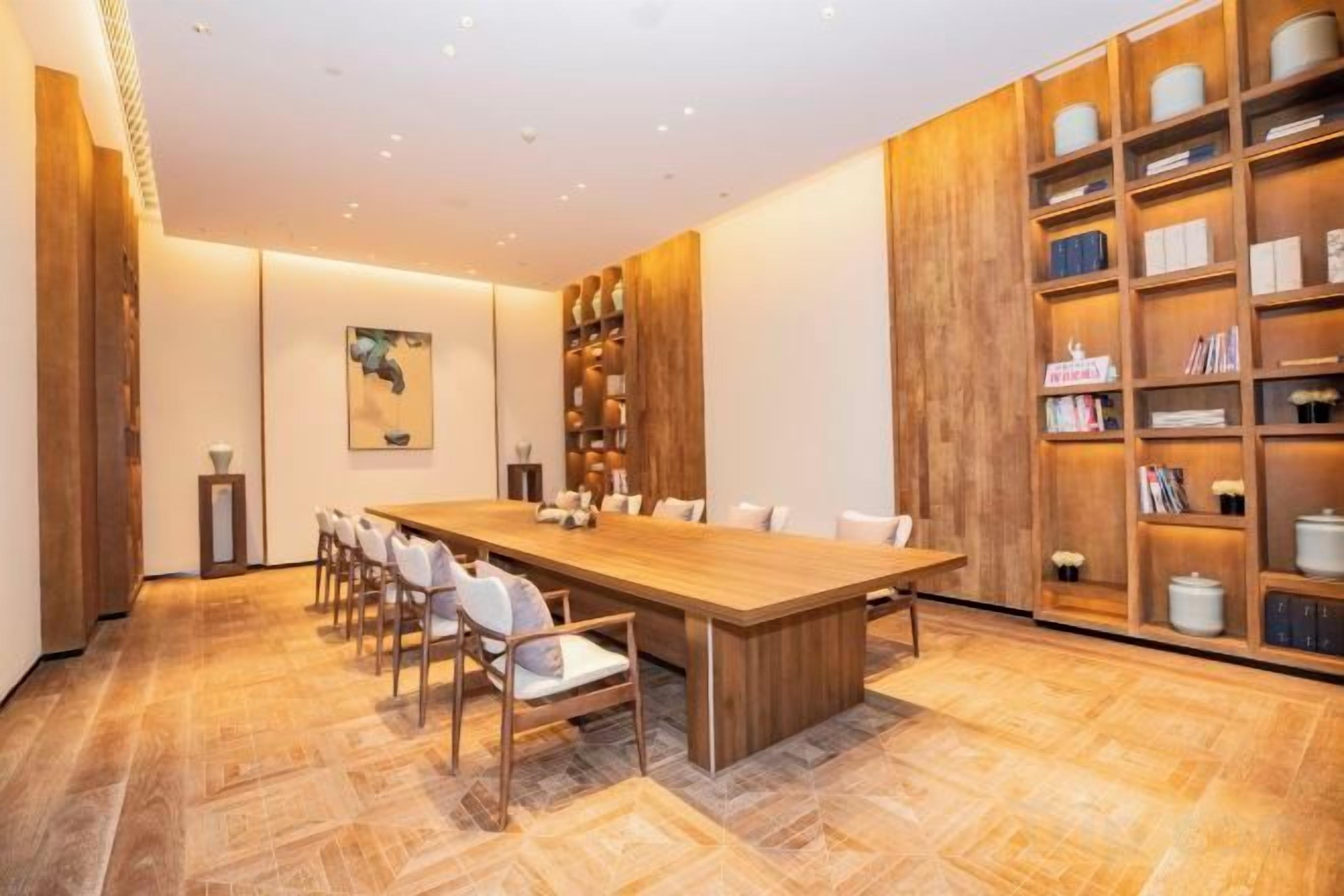 A conference room with a long table, chairs, and bookshelves.