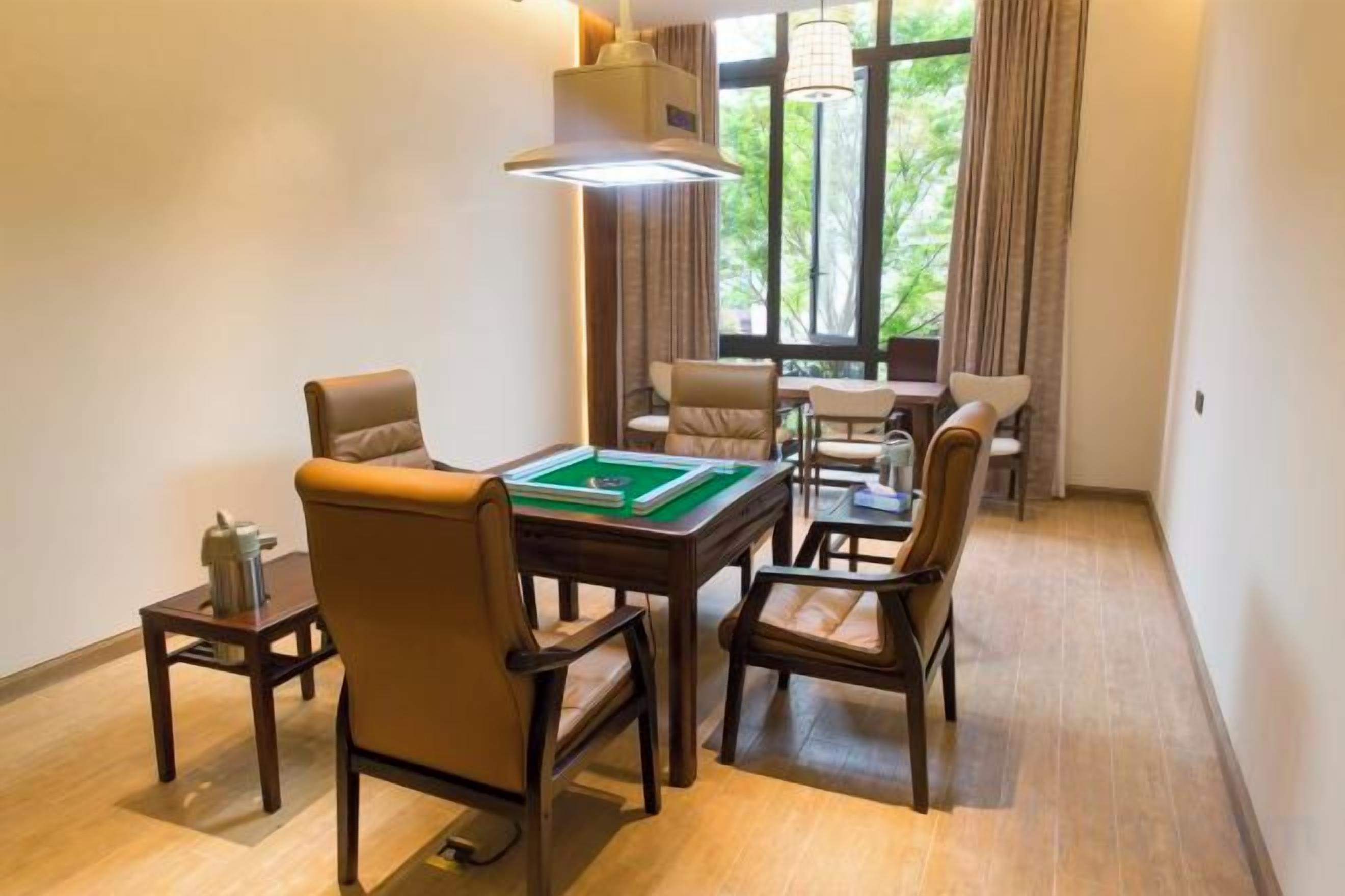 A room with a pool table, leather chairs, a sofa, and a window with curtains.