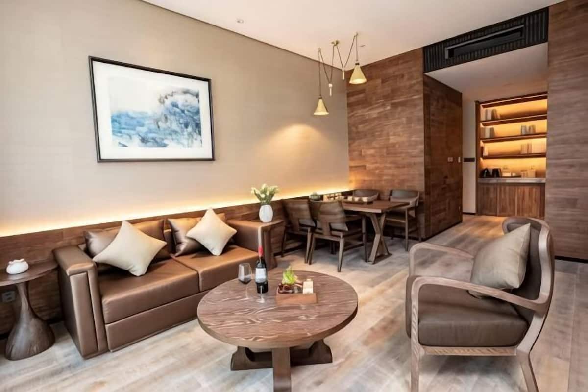 A modern living room with a sofa, armchairs, a dining table, and a coffee table.