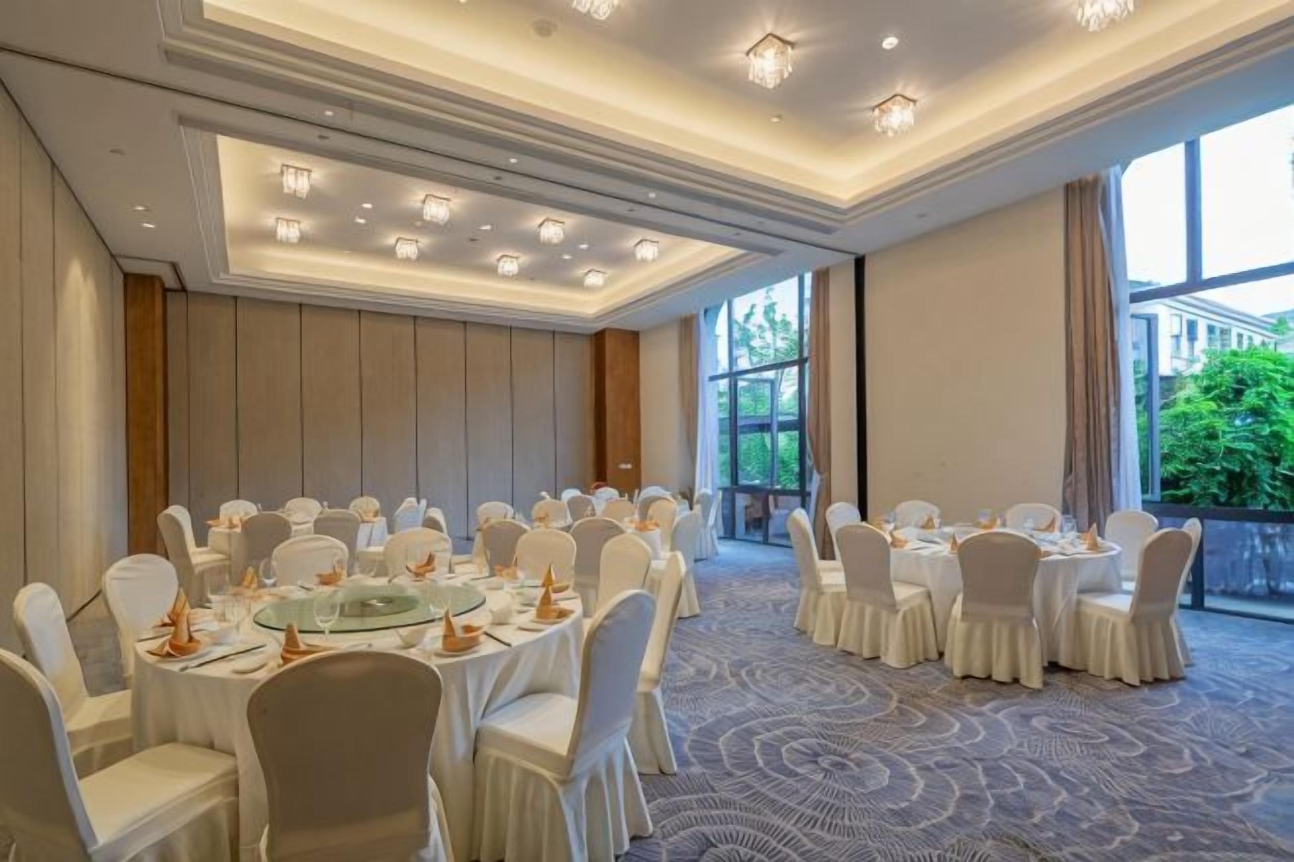 A conference room with round tables, white chairs, and a carpeted floor.