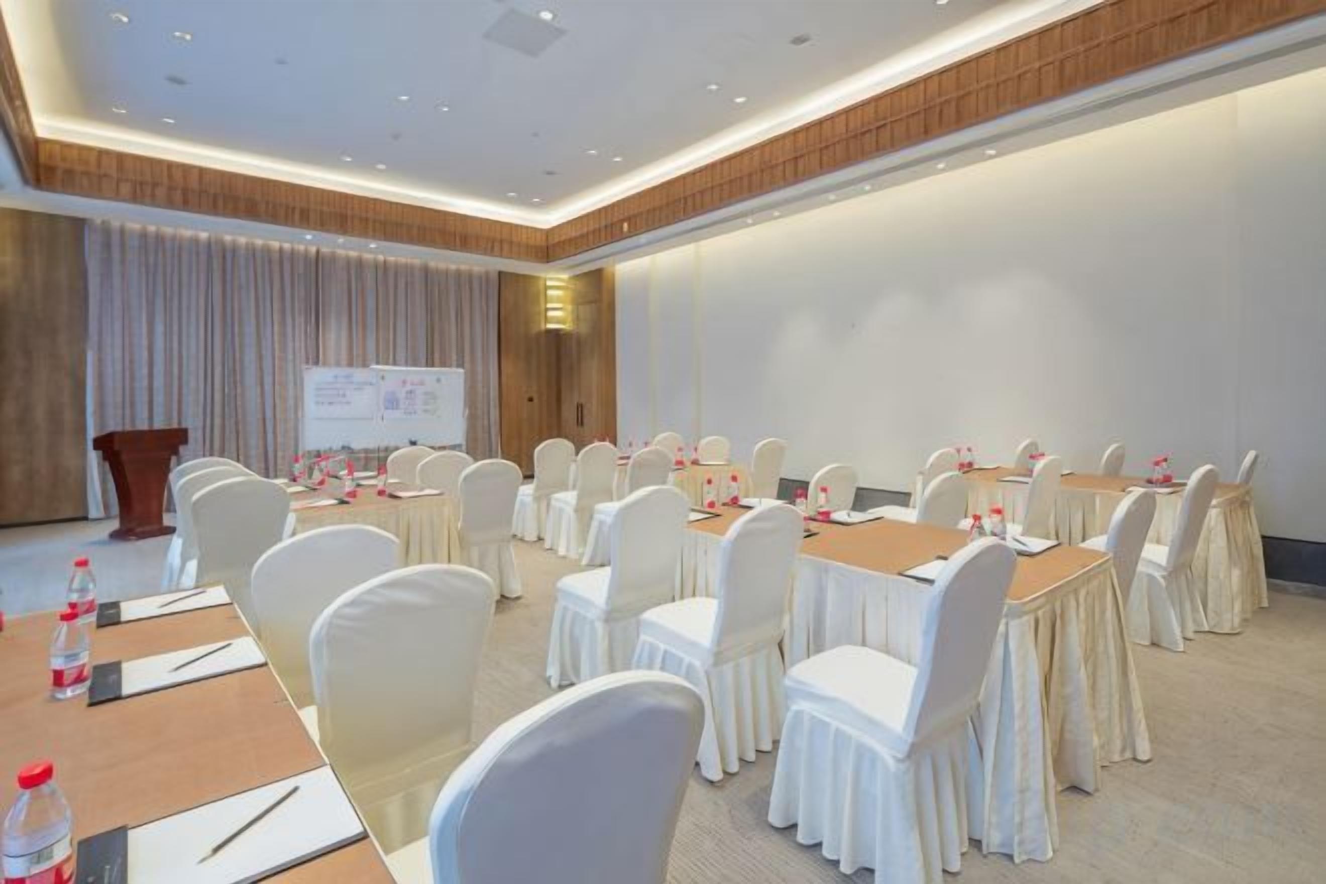 A conference room with round tables, white chairs, and a podium.