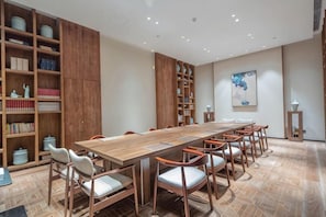 Une salle de conférence avec une longue table en bois, de nombreuses chaises et des étagères remplies de livres.