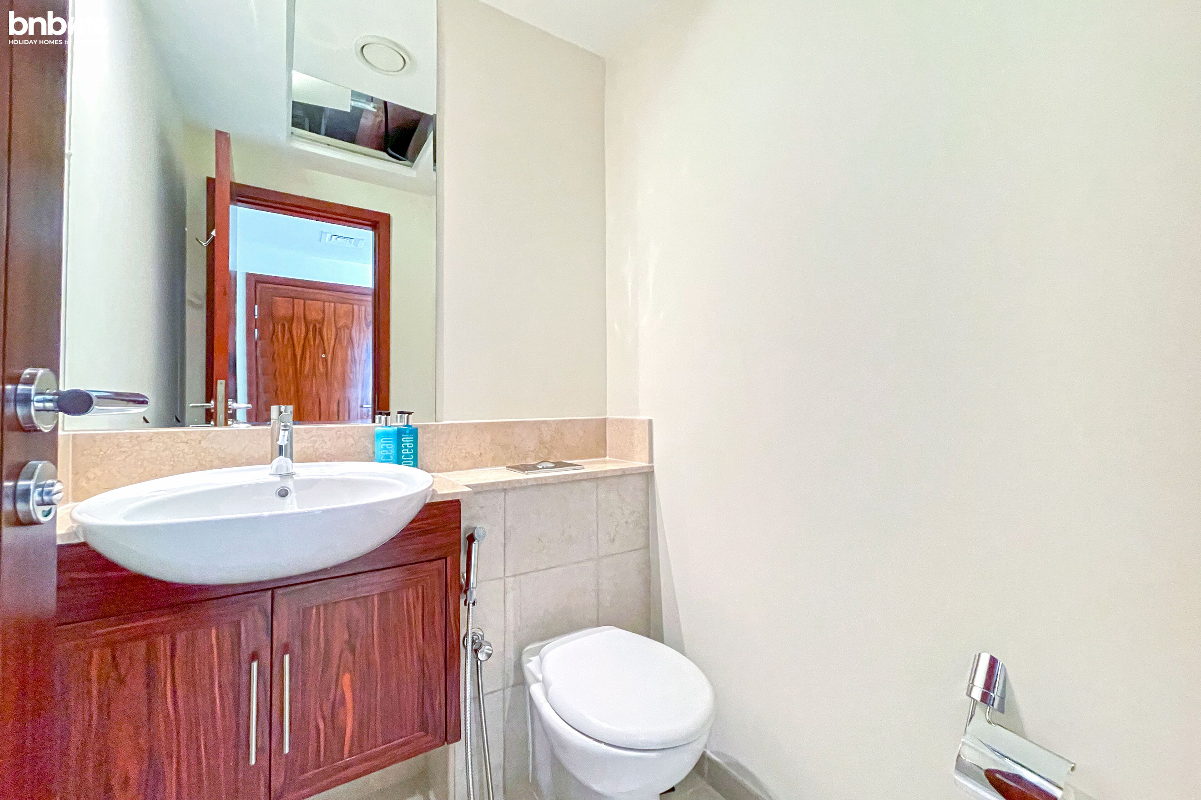 A bathroom with a white sink, wooden vanity, and a toilet.