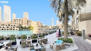 A waterfront patio with outdoor seating and a view of the city skyline. - bnbme | The Residences | 2 BDR (Dubai)