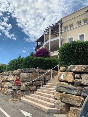 A stone staircase leading to a building with a balcony, a no entry sign, and a sign indicating the building is for sale.