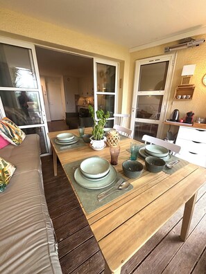 Een eetgedeelte met een houten tafel gedekt voor vier personen, omringd door een bank en een keuken op de achtergrond.