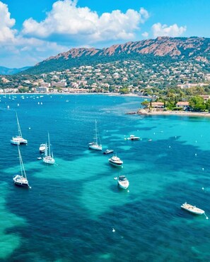 A coastal town with clear turquoise waters, sailboats, and a mountainous backdrop. - Le Jardin de L'Esterel FH007 Residence Club Heated pool Parking, air conditioning (Saint-Raphaël)