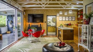 Eine moderne Küche mit Einbauofen, ein Essbereich mit roten Stühlen und ein großer Flachbildfernseher an der Wand.