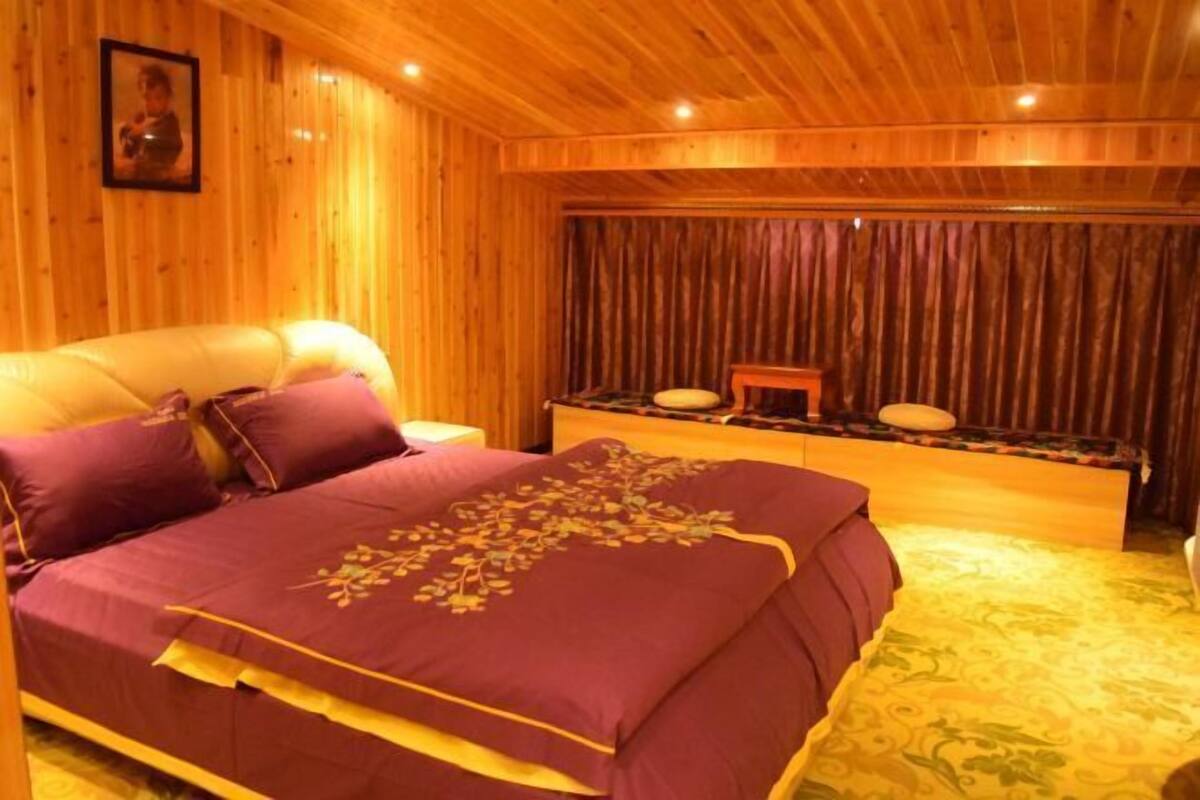 A wooden-paneled room with a bed, a small table, and a curtain.