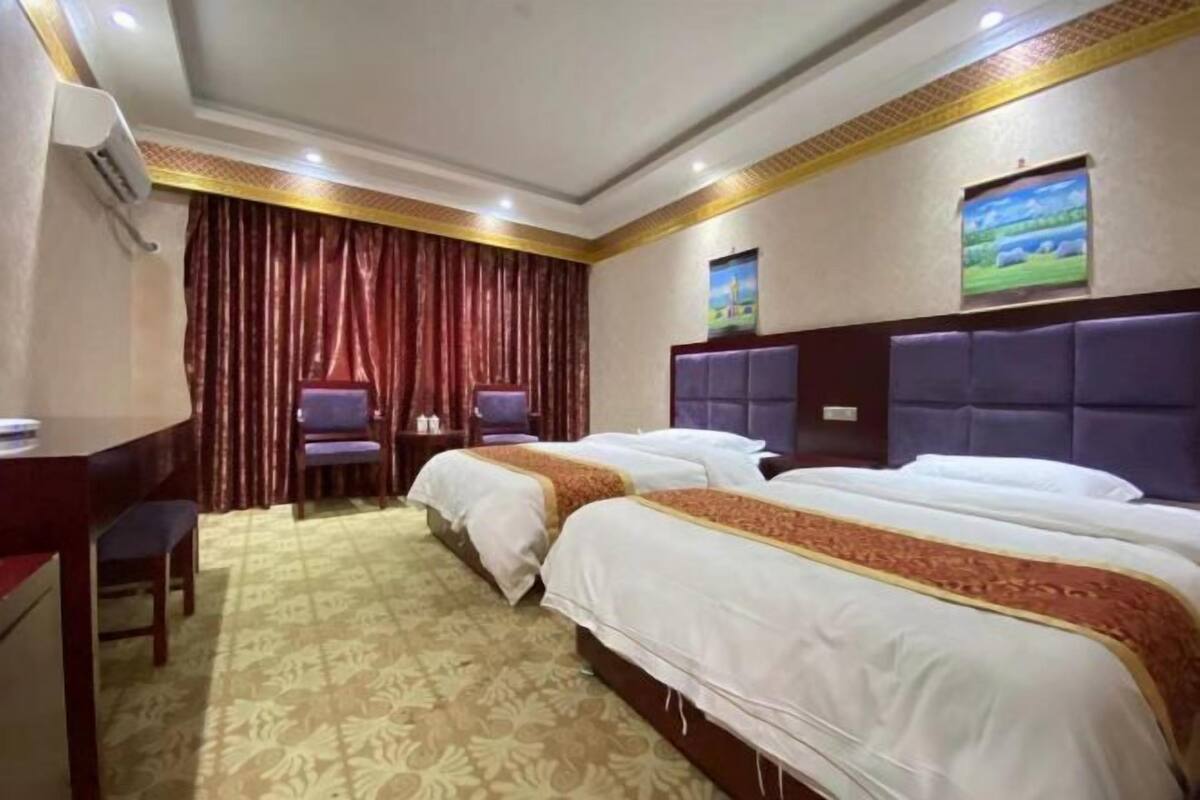 A hotel room with two beds, a desk, and a chair.