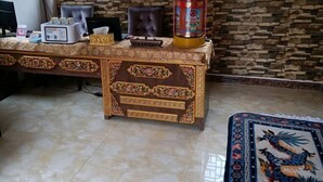 Una habitación con un escritorio de madera decorativo, una computadora y una vela tradicional.