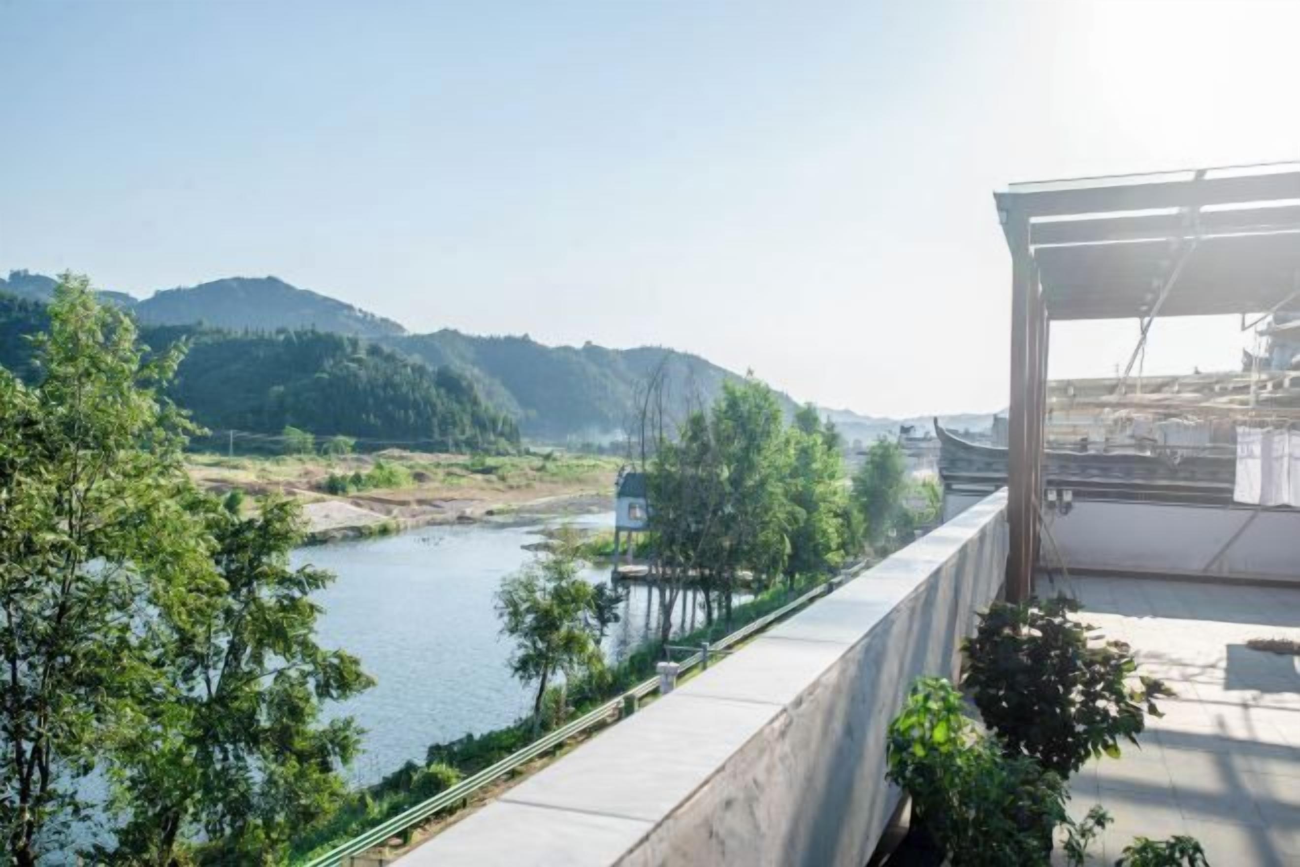 A riverside view with a concrete walkway and greenery.