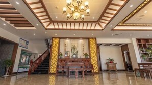 Eine Lobby mit einer Holztreppe, einer Chandelüstere und einem Empfangsbereich.