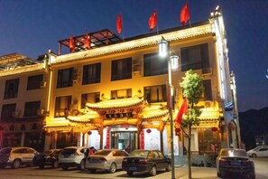 A hotel with traditional architecture, multiple floors, and a parking lot with cars.