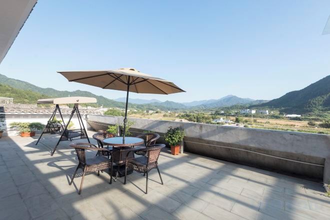 An outdoor patio with a table and chairs, a swing, and a view of mountains.