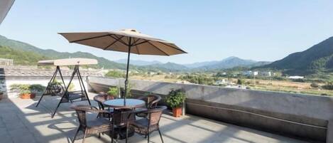An outdoor patio with a table and chairs, a swing, and a view of mountains.