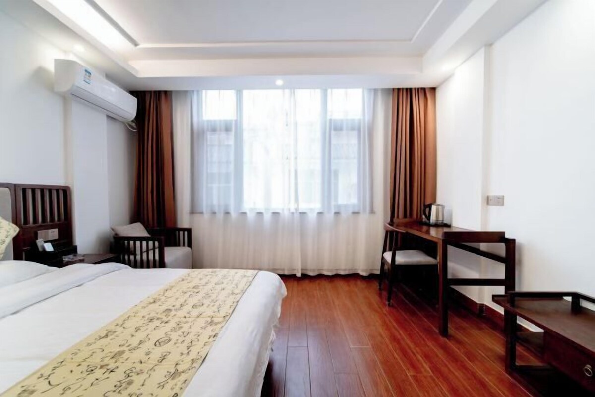 Ein Hotelzimmer mit einem Bett, einem Schreibtisch, einem Stuhl und einem fenster mit Vorhängen.