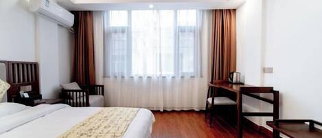 Une chambre d’hôtel avec un lit, un bureau, une chaise et une fenêtre avec des rideaux.