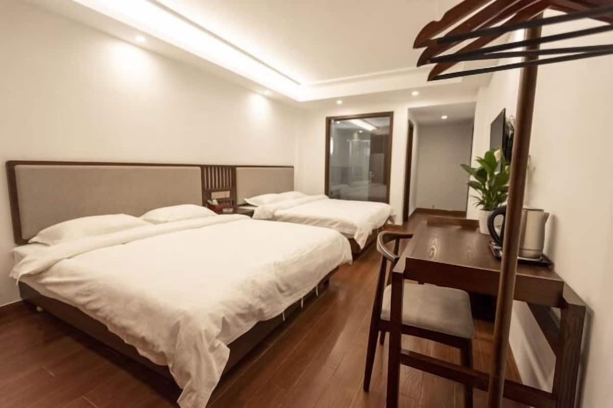 Hotellihuone, jossa on kaksi sänkyä, puinen työpöytä ja tuoli.