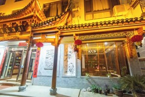Un bâtiment traditionnel avec un toit en tuiles, une devanture de magasin et des plantes en pot à l’extérieur.