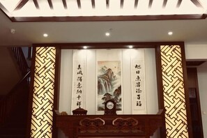 Un interior chino tradicional con un aparador de madera, pergaminos de caligrafía y un reloj.