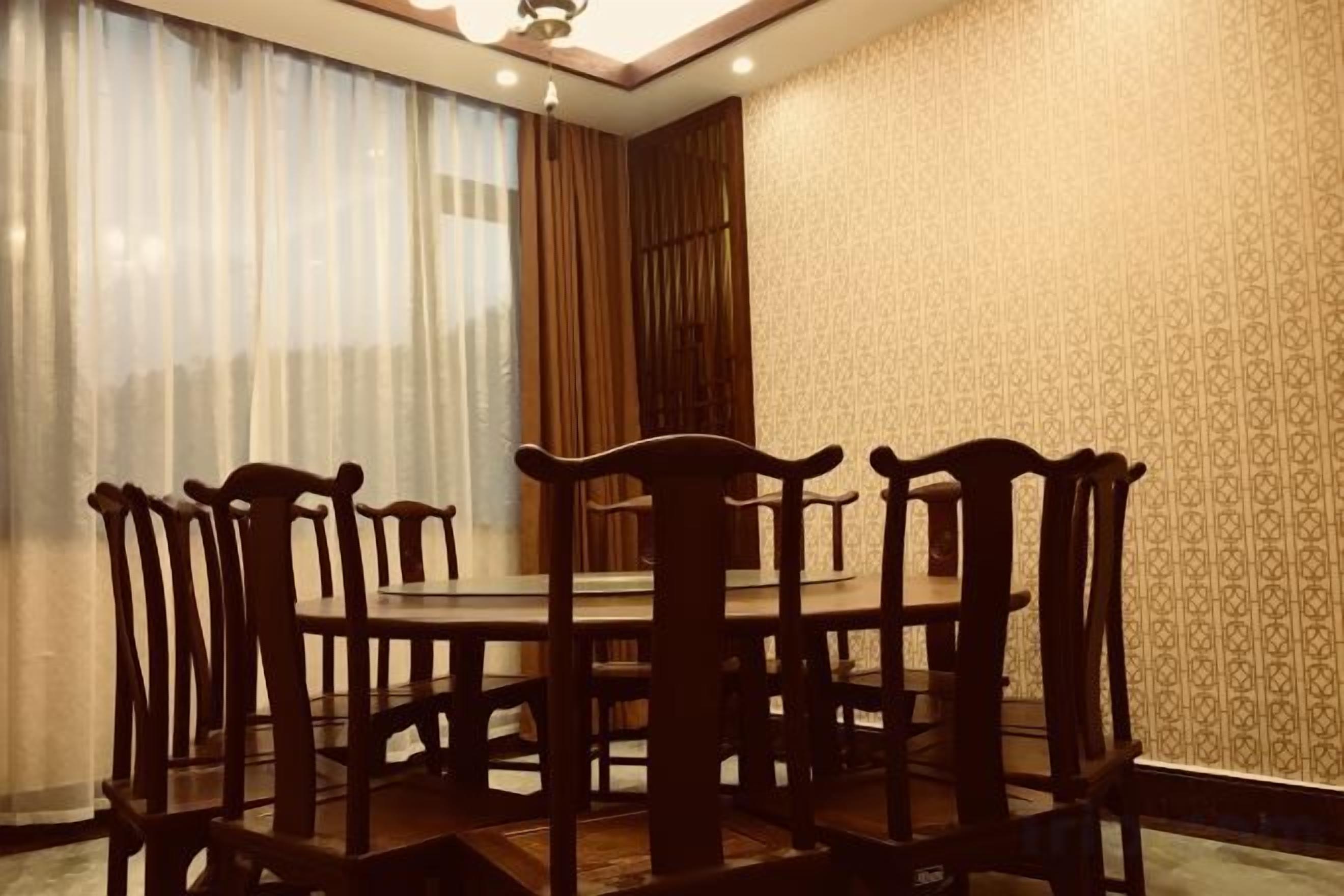 A dining area with a round table and chairs, a ceiling fan, and a patterned wall.