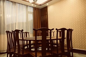 Un comedor con una mesa redonda y sillas, un ventilador de techo y un papel tapiz estampado.