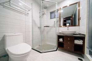 A modern bathroom with a glass-enclosed shower, a white toilet, and a vanity with a large mirror and a vessel sink. - Wuyuan Qingyun Hotel (Wuyuan)
