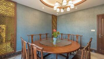 Une table de salle à manger ronde, avec des chaises, un lustre et un panneau décoratif mural.