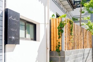 A black welcome sign with white cursive text on a building facade. - Amila Guesthouse (Dali City)