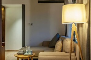A cozy living room with a beige sofa, a round wooden coffee table, and a floor lamp. - Amila Guesthouse (Dali City)