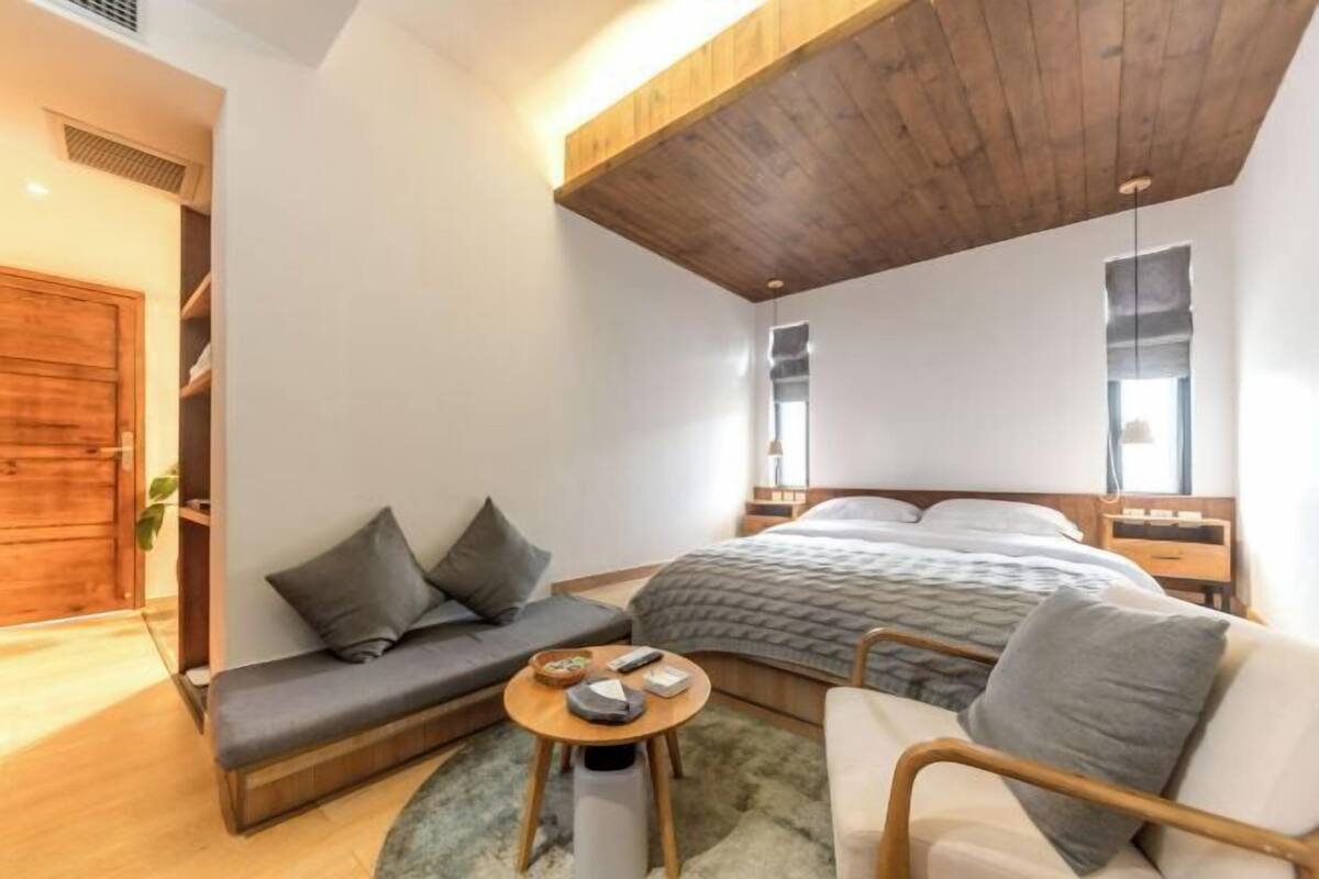 A compact hotel room with a bed, a sofa, a small table, and a chair.