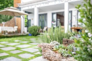 A garden with a stone pathway leading to a house with a covered patio. - Amila Guesthouse (Dali City)