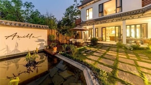 A modern house with a well-maintained garden, a paved patio, and a swimming pool. - Amila Guesthouse (Dali City)
