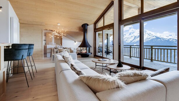 A spacious living area with a large sofa, a dining table, and a fireplace. - New rooftop with south balcony, parking and wifi (Montvalezan-La Rosière)