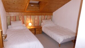 Ein Schlafzimmer mit zwei Einzelbetten, einem Nachttisch mit Lampe und einer schrägen Decke mit Dachfenster.